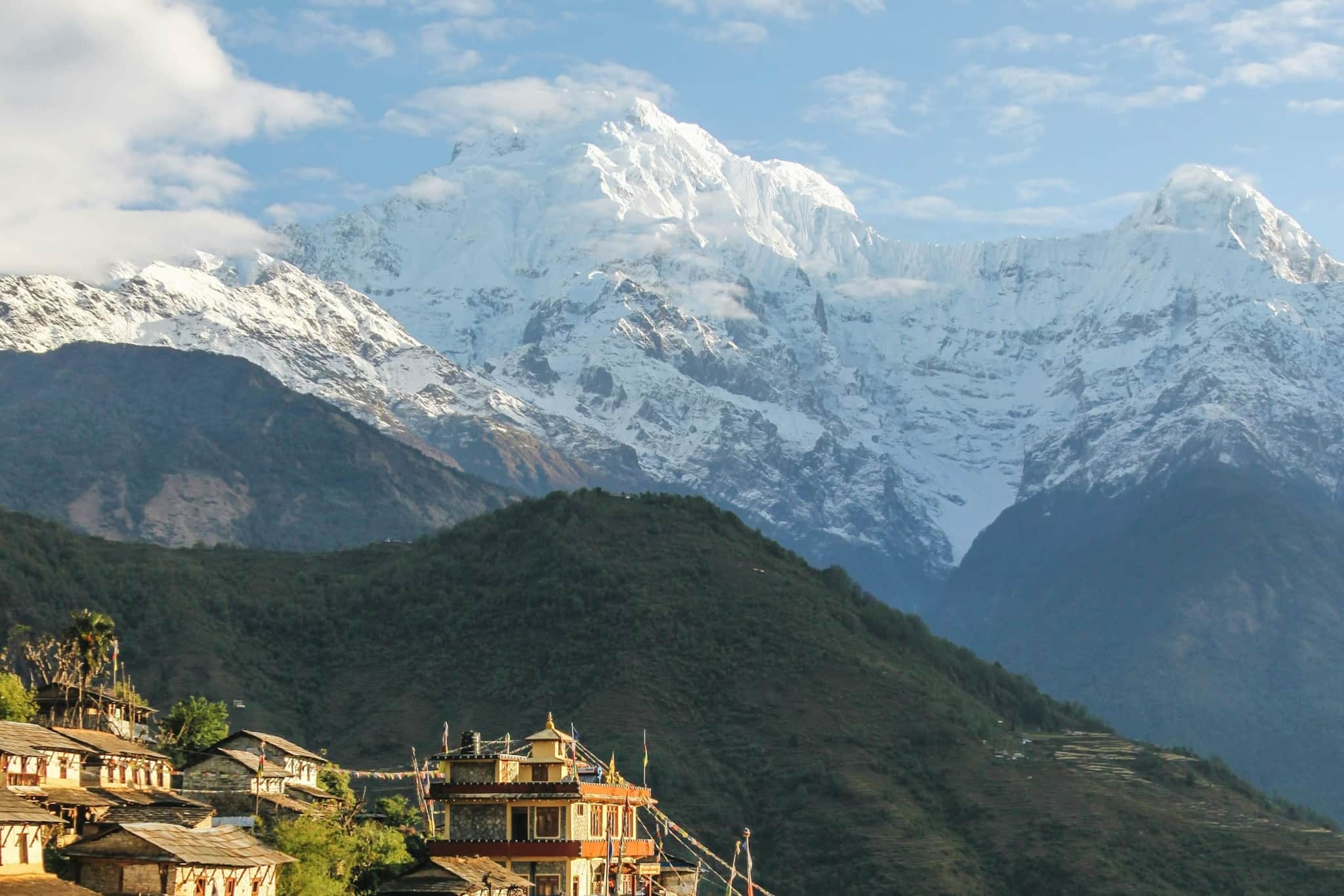 A Gurung village of stone houses on terraced hillside below the snow peaks of Annapurna South and Hiunchuli